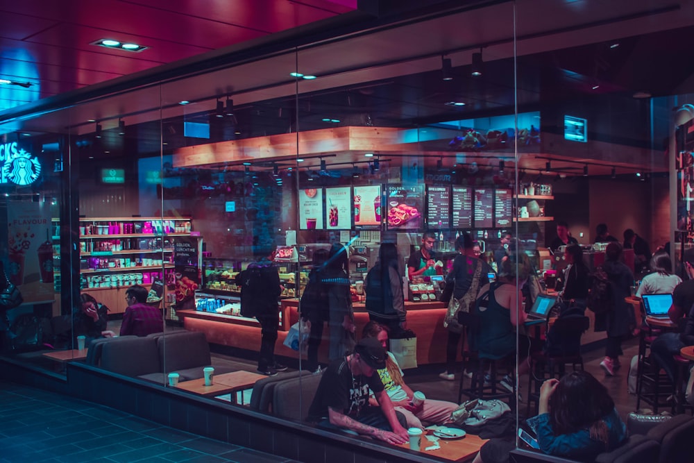 people walking and sitting inside cafe during nighttime