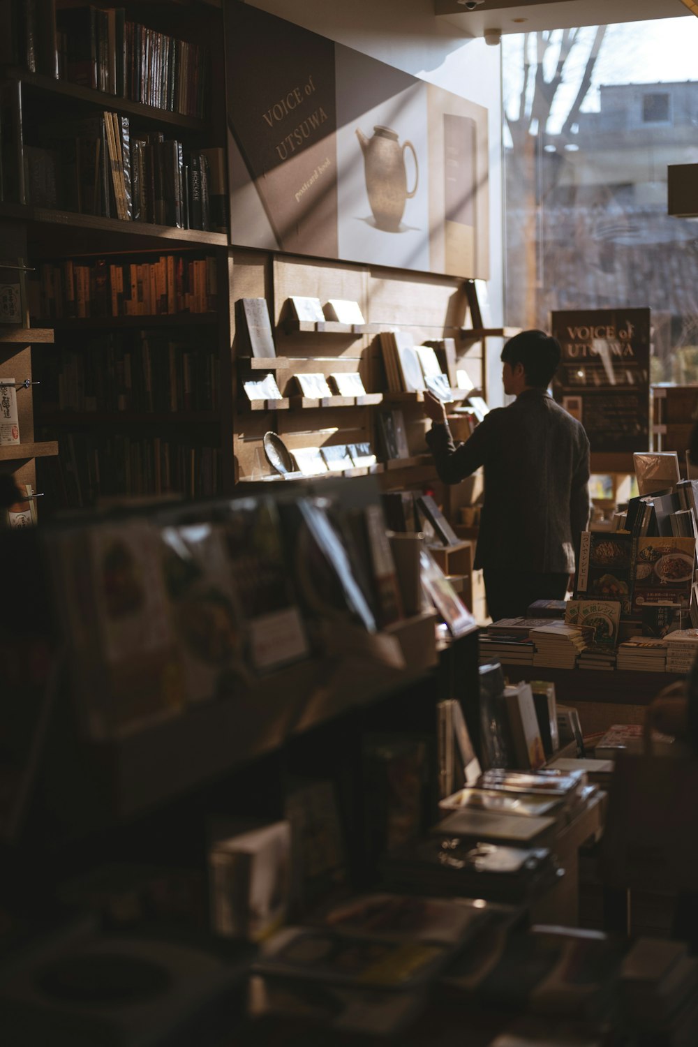 Mann, der in der Bibliothek steht und Bücher findet