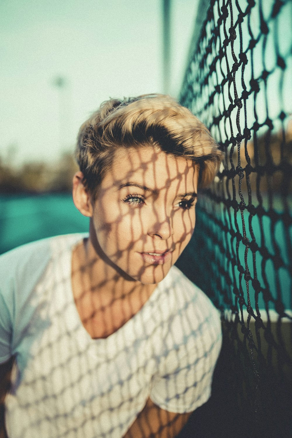 close up photo of woman with V-neck t-shirt close to black net