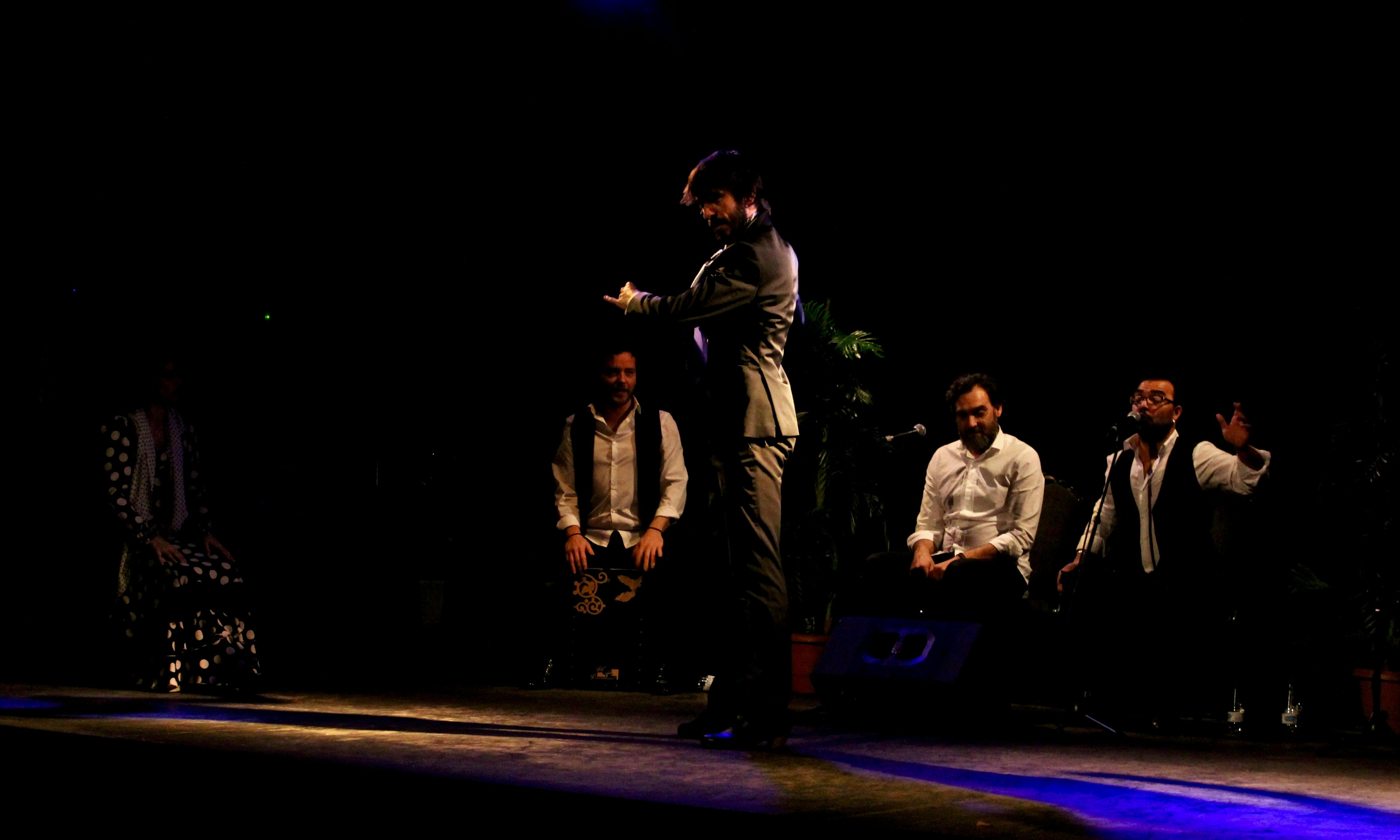 Dark festival stage with multiple performers, dramatic lighting