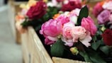 A set of colorful artificial roses displayed in a rustic wooden crate.