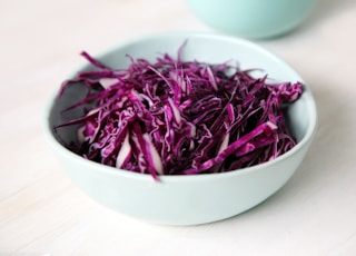 selective focus photography of purple petal filled bowl