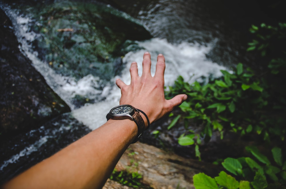 person reaching body of water