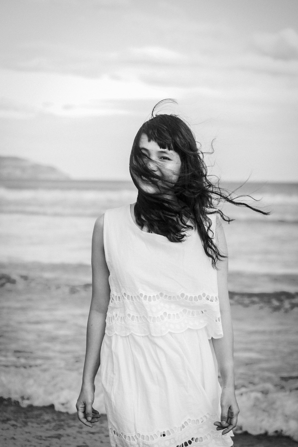 grayscale photography of woman standing on seashore