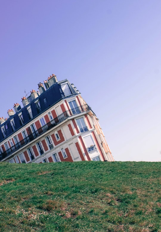 white and red leaning building under blue sky in Square Louise Michel France