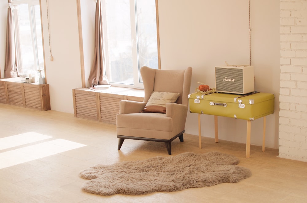 wing chair beside suitcase and window