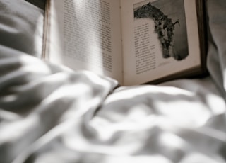 opened-book on top of bed sheet