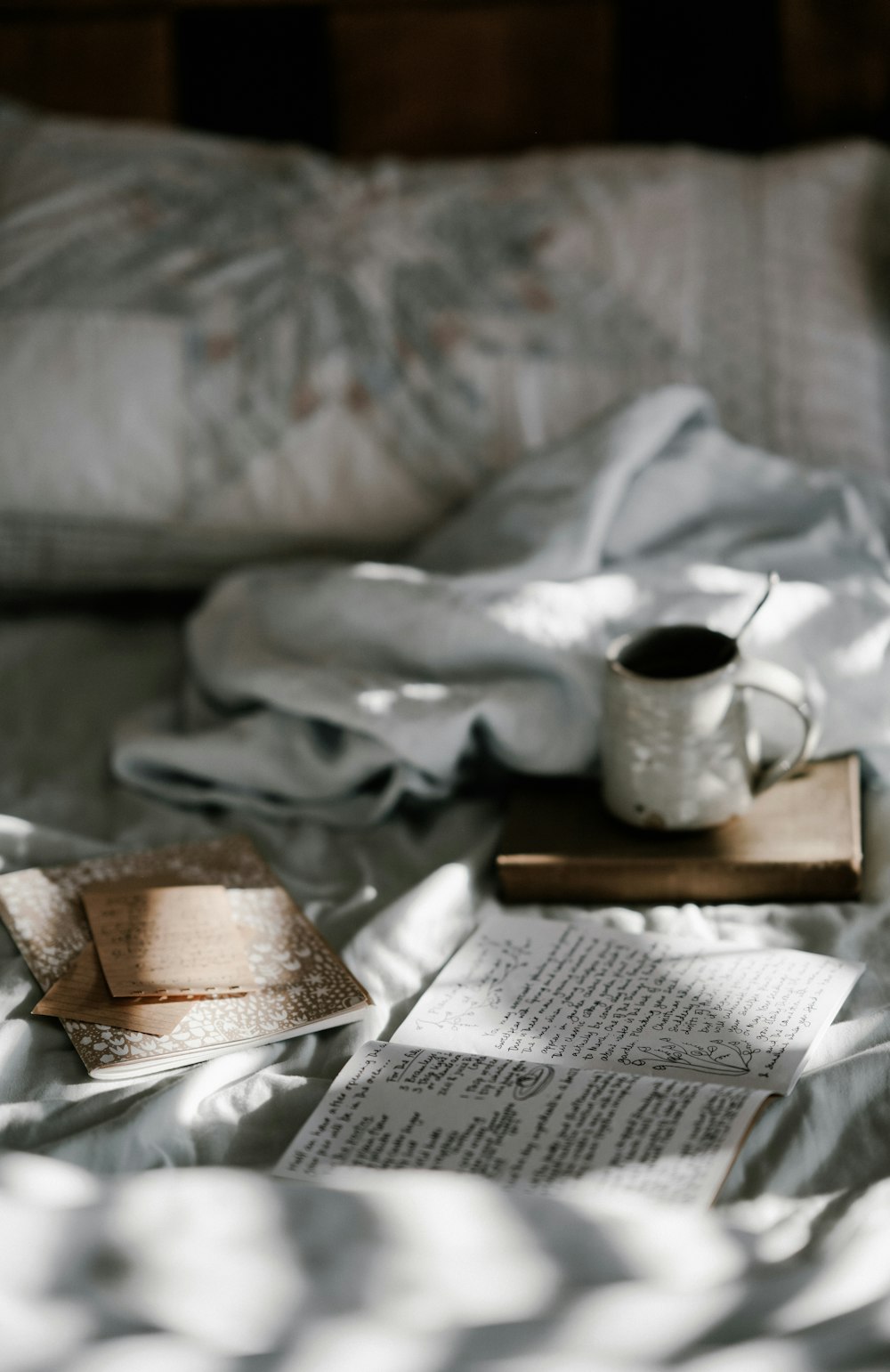 白い毛布の近くの茶色の木製コースターの上のコーヒーマグ