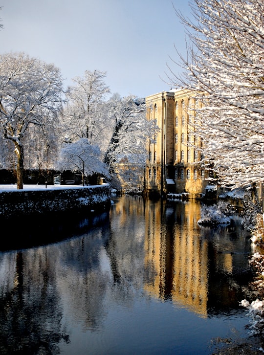 brown concrete building near river and trees in Bradford-on-Avon United Kingdom