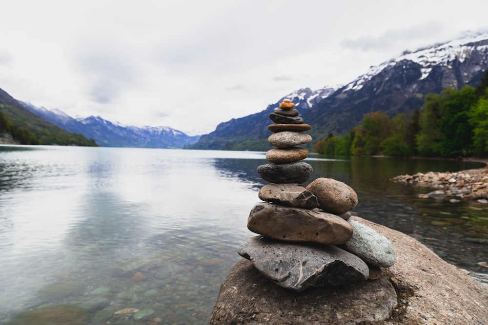 a stack of rocks sitting on top of a rock near a lake