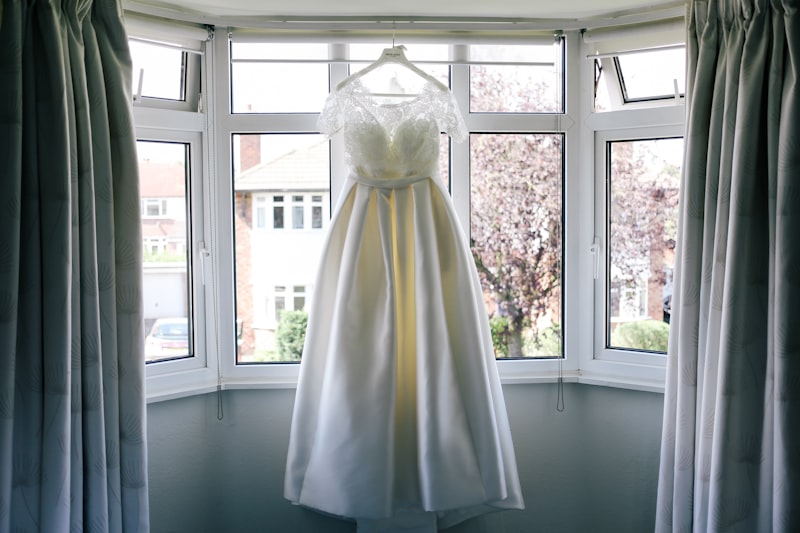 The bride's dress hanging in window light before the ceremony