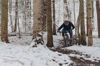 man riding bicycle on snow covered field