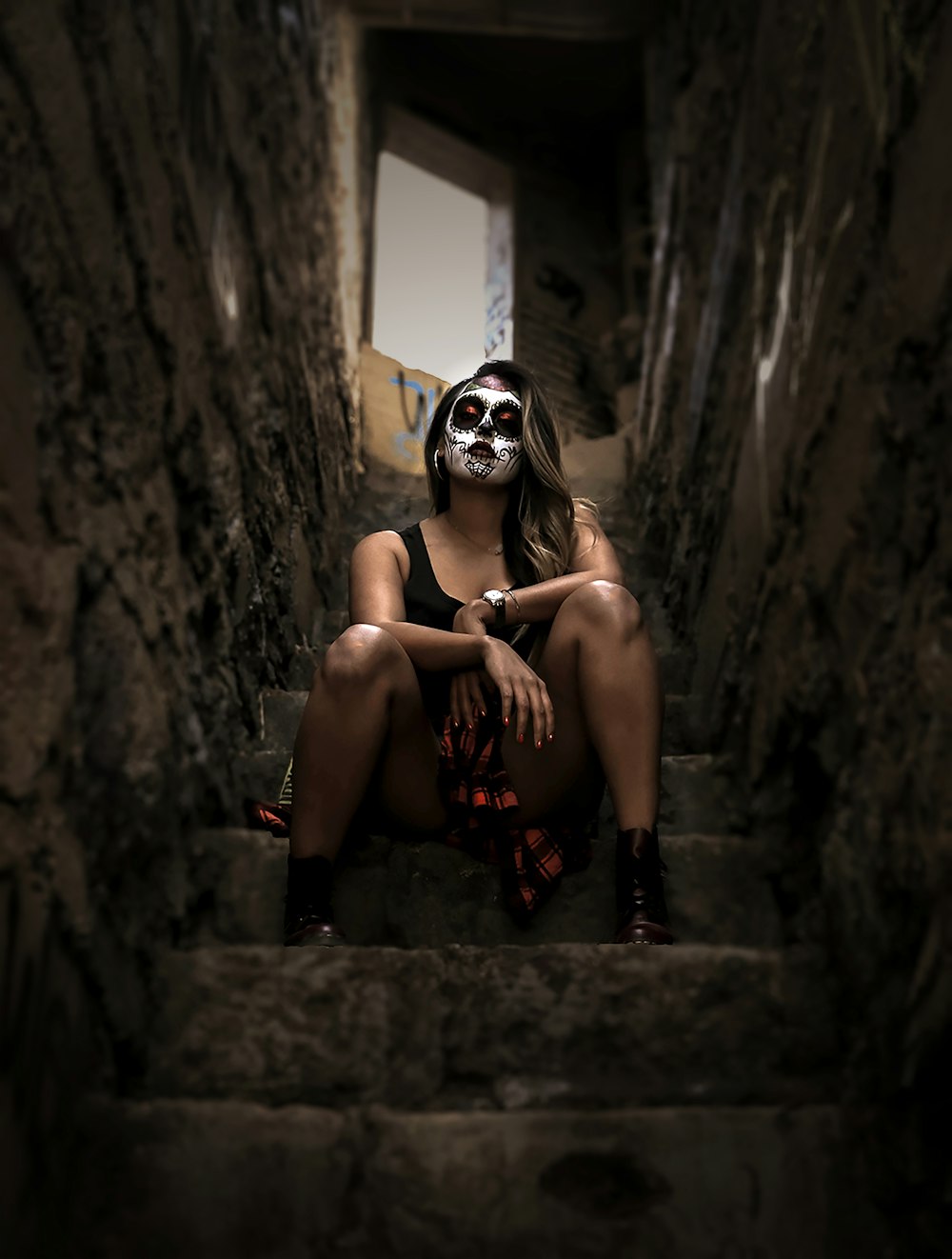 woman wearing skull face paint sitting on stairs