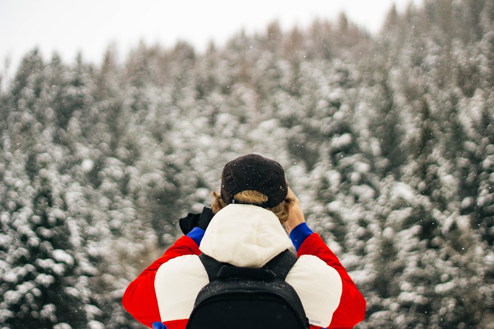 man standing near pine trees covered with snow