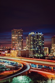 timelapse photography of red and orange light crossing on road near city during nighttime