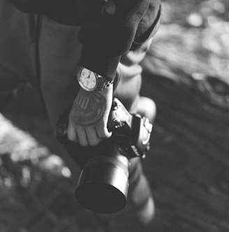 grayscale photo of person holding DSLR camera