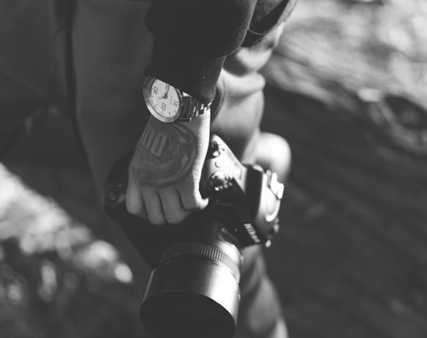 grayscale photo of person holding DSLR camera