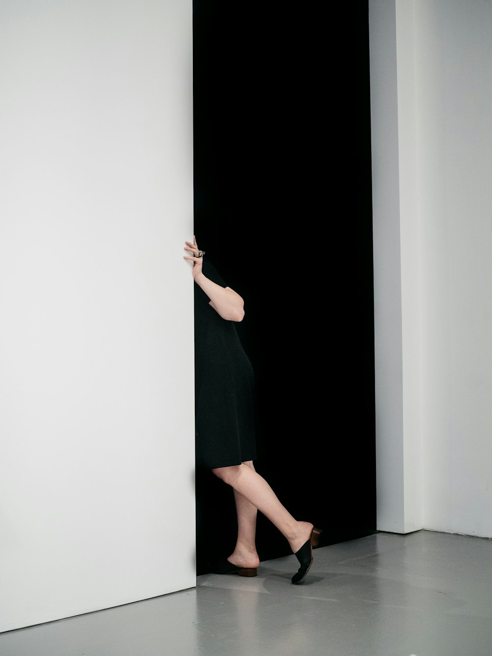 mulher em pé se esgueirando na porta dentro da sala pintada de branco