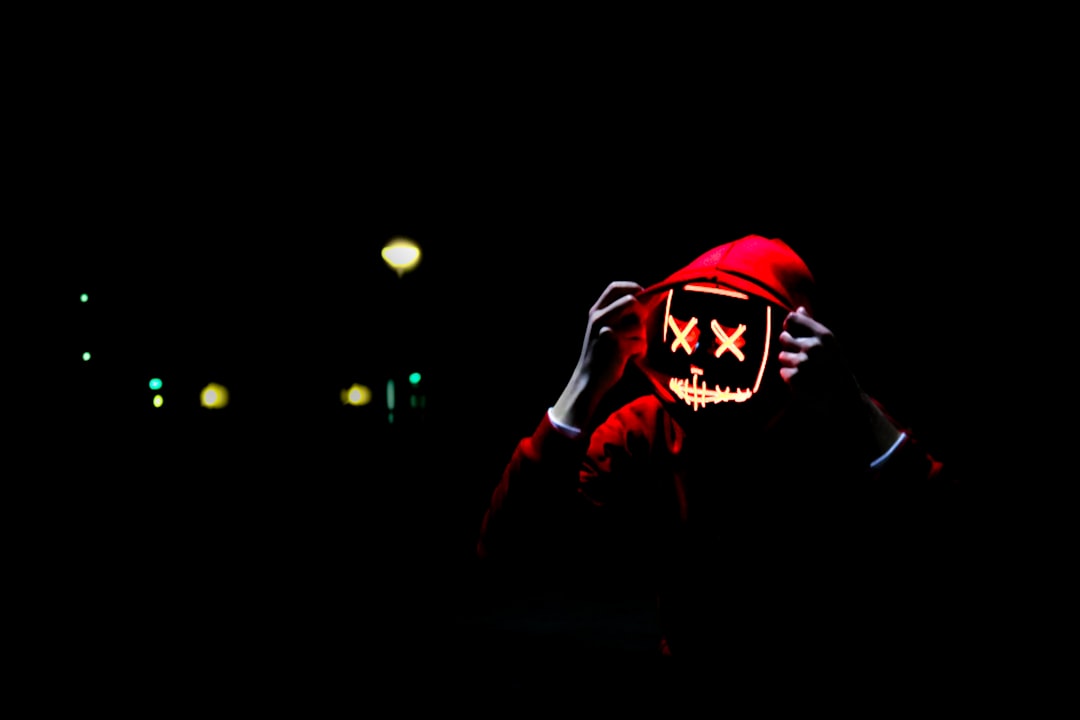 person wearing hoodie and neon mask