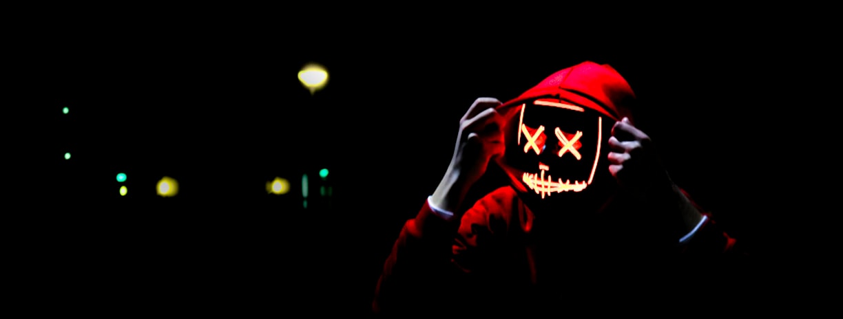 person wearing hoodie and neon mask