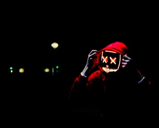 person wearing hoodie and neon mask