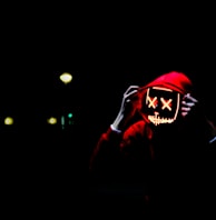 person wearing hoodie and neon mask