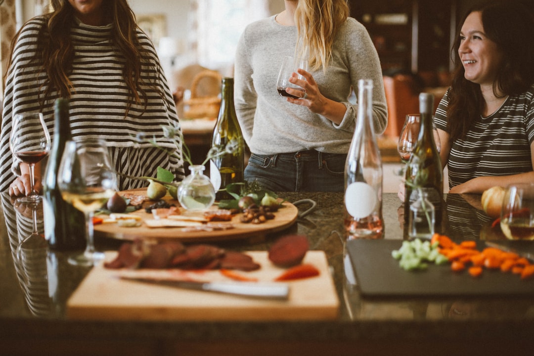 two woman standing beside woman sitting in front of table,