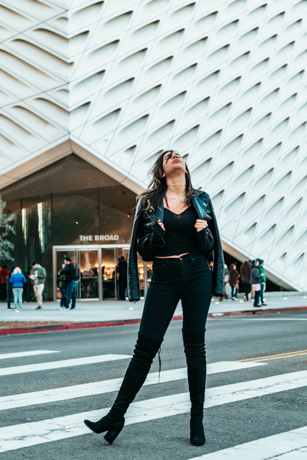 woman standing on pedestrian lane looking up beside white building