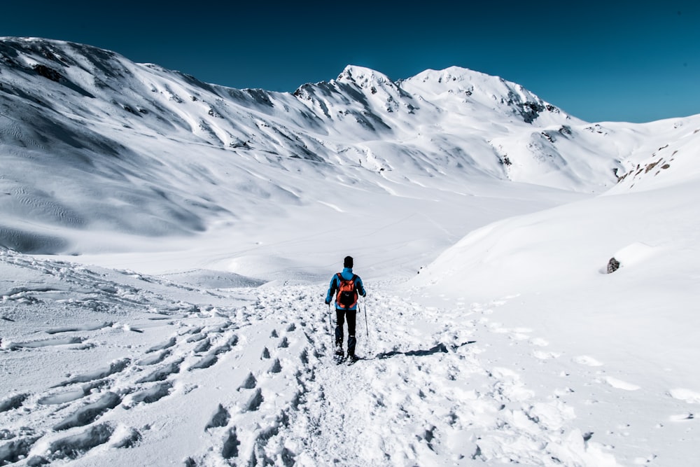 山の近くの雪原を歩く男