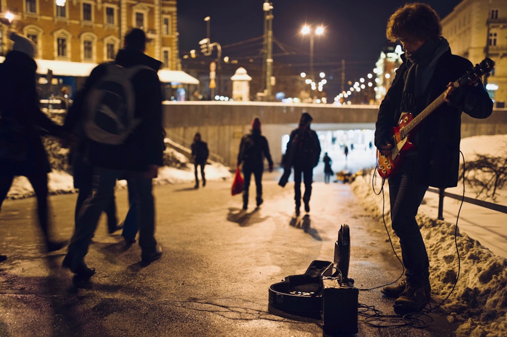 uomo che suona la chitarra sulla strada durante la notte