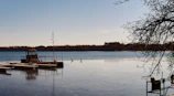 A peaceful lakeside dock with a small boat resting on calm water.