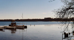 A peaceful lakeside dock with a small boat resting on calm water.