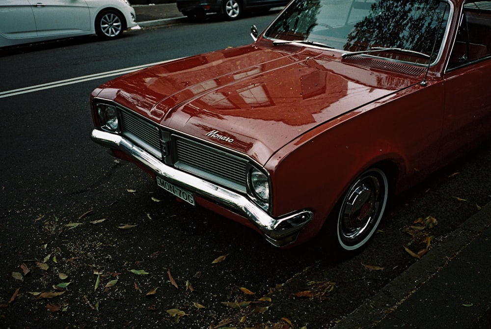 classic red vehicle park beside road at daytime