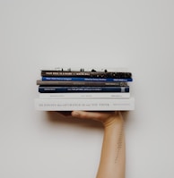 person holding pile of books