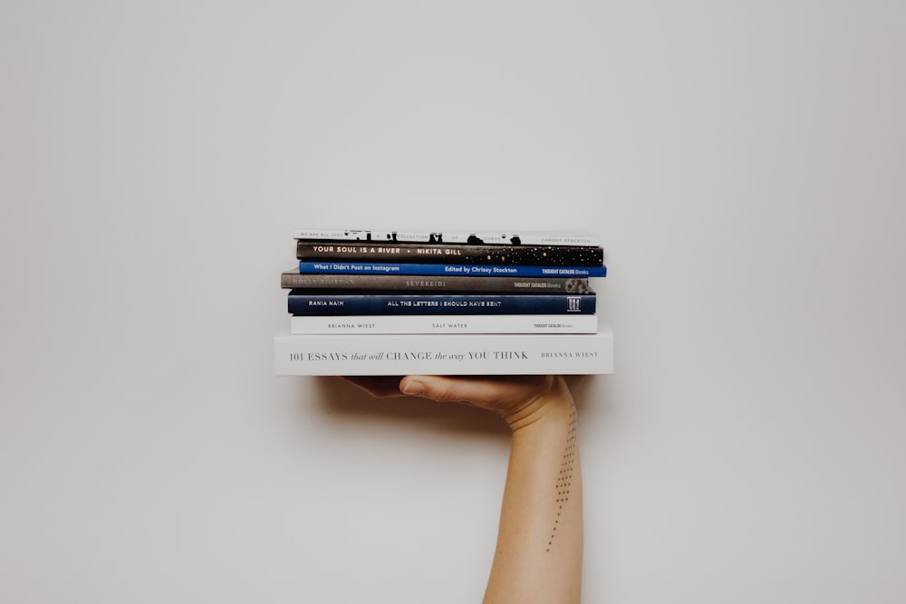 person holding pile of books