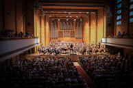 A panoramic view of an orchestral concert hall filled with musicians during a jazz performance.