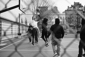 grayscale photo of group of men playing street basketball