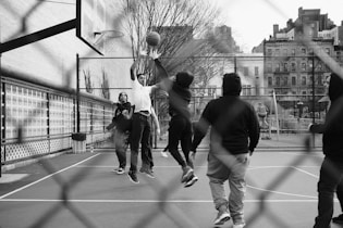 grayscale photo of group of men playing street basketball