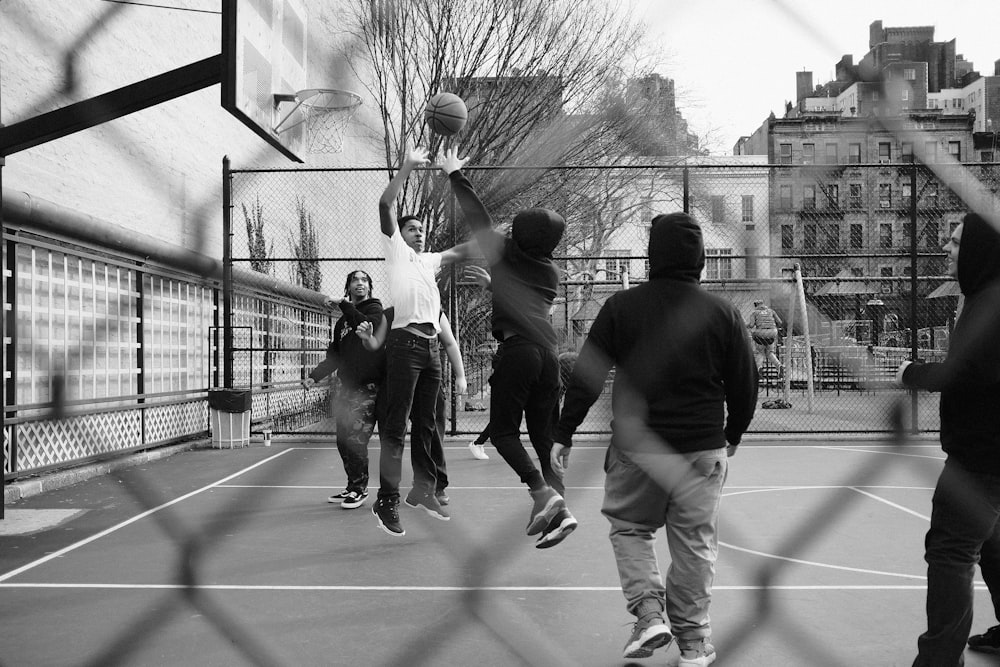 grayscale photo of group of men playing street basketball
