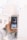 A hand is holding a smartphone with an application open on the screen. The background appears to be a blurred cityscape with tall buildings. The smartphone screen displays profile information and various statistics relating to the profile.