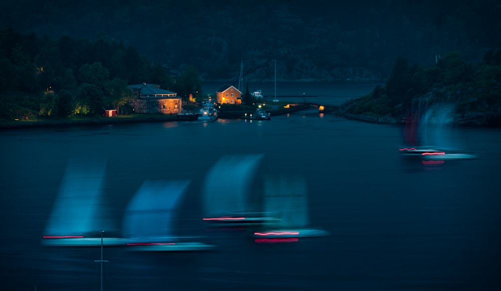 boats on body of water near lighted house
