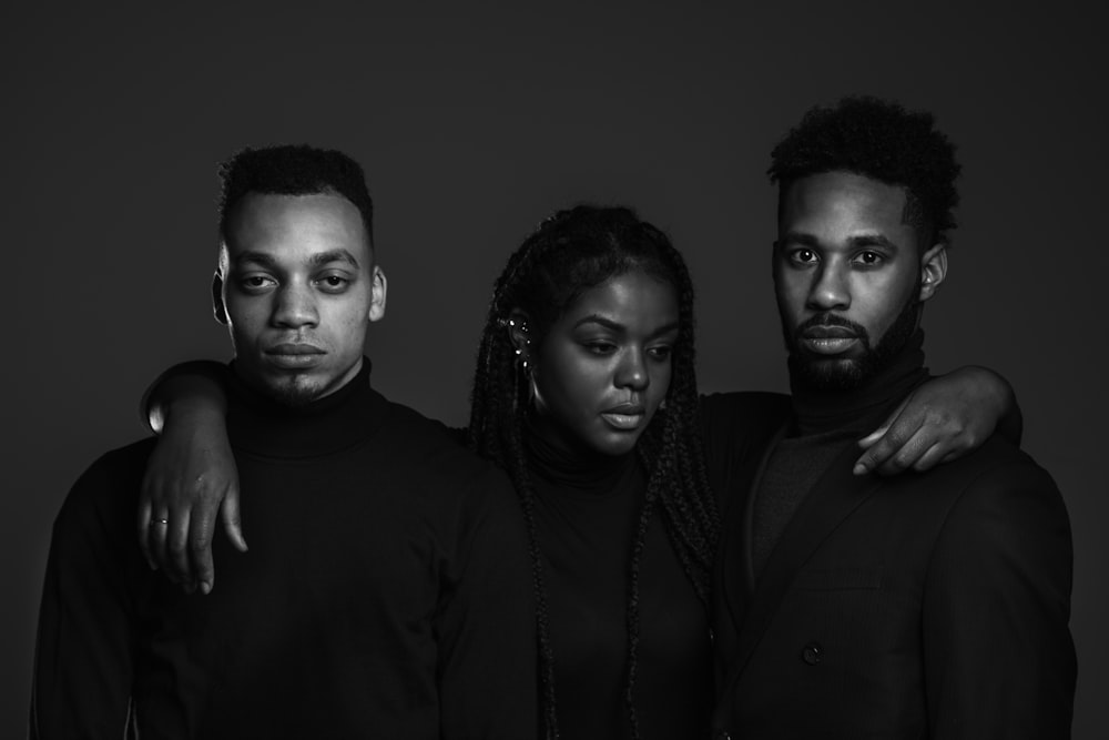 grayscale photo of woman standing between two men