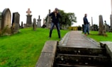 Volunteers carefully photographing weathered headstones under a sunny sky.