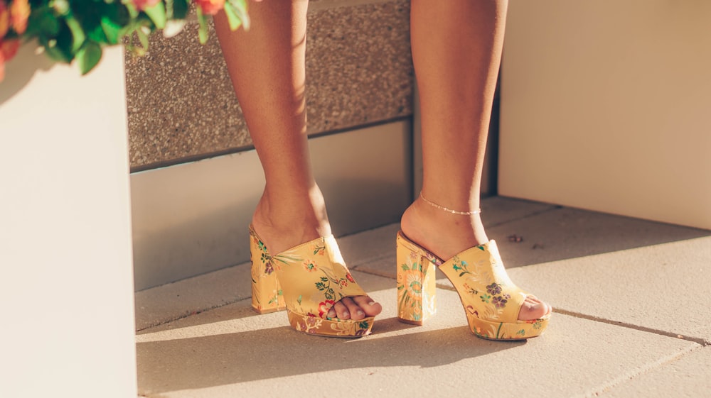 woman wearing yellow sandals standing near brown wall