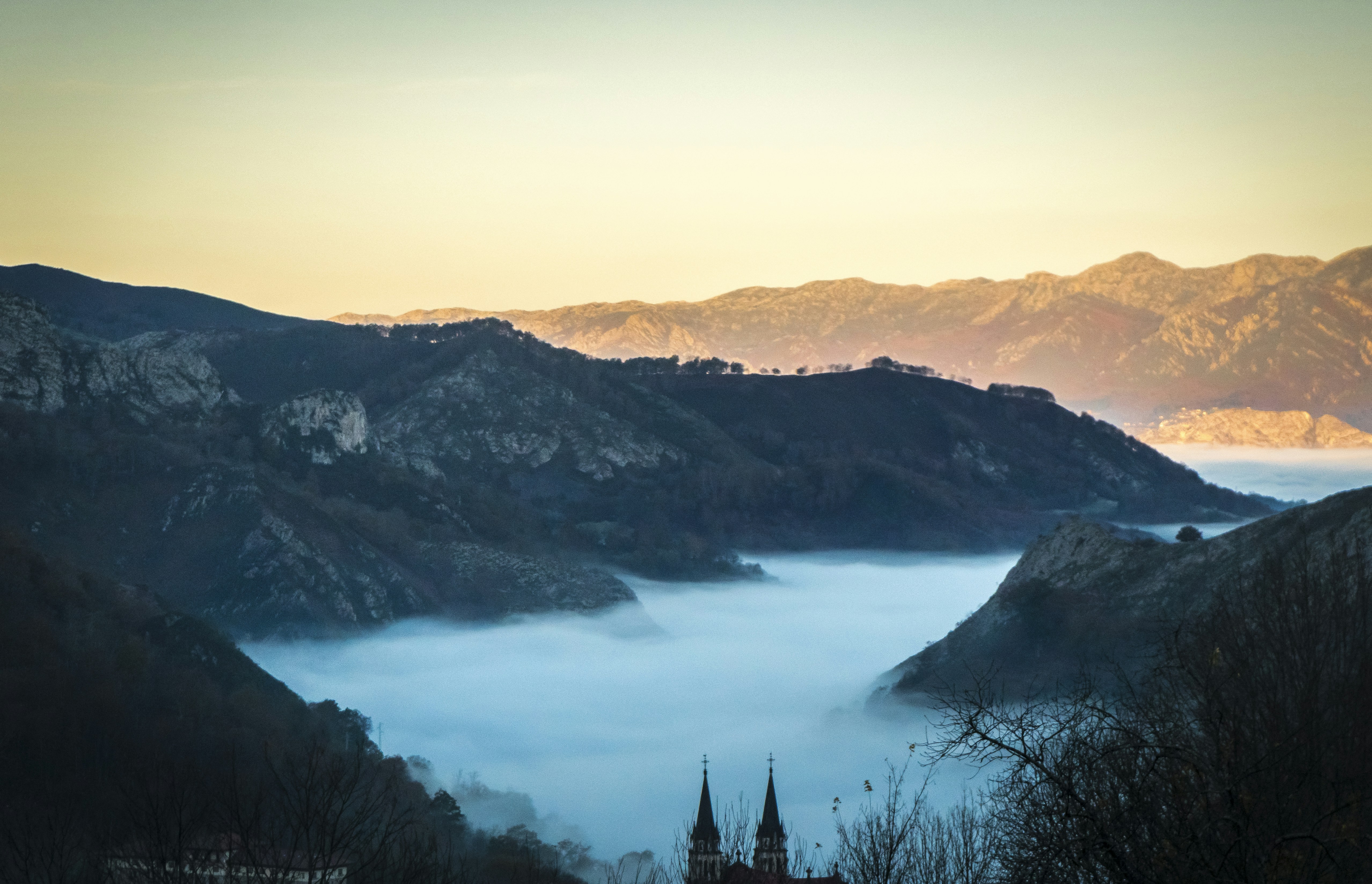 landscape photo of fogs between gray mountains at daytime
