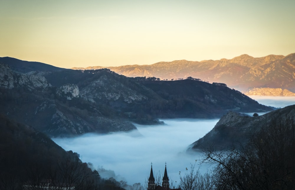 昼間の灰色の山々の間の霧の風景写真