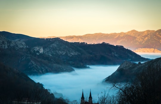 landscape photo of fogs between gray mountains at daytime in Sanctuary of Covadonga Spain