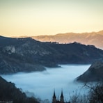 landscape photo of fogs between gray mountains at daytime