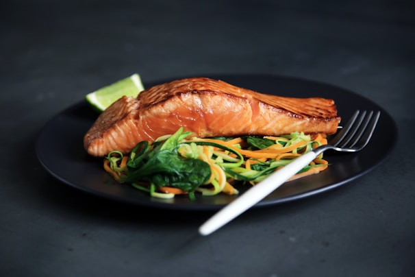 grilled fish, cooked vegetables, and fork on plate