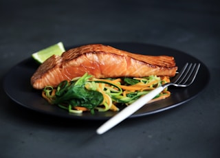 grilled fish, cooked vegetables, and fork on plate